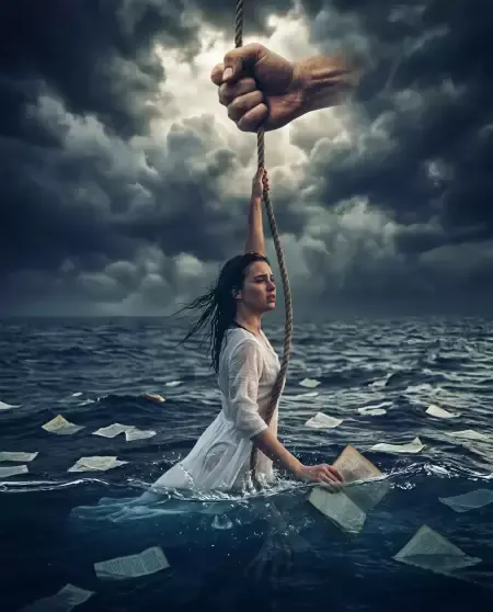 Woman gripping rope from sky in dark ocean